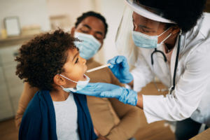 A family doctor checking the throat of a young patient.