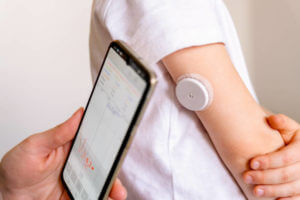 ystem of continuous monitoring of glucose on child's arm. Measuring blood sugar using a mobile phone, diabetes type 1.